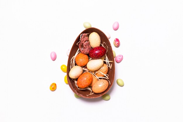 Concetto dell'alimento di festa caramelle variopinte e uova di pasqua del cioccolato su fondo bianco