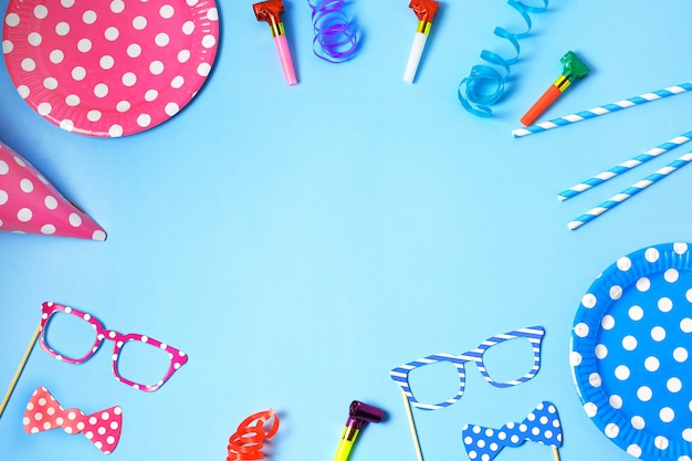 Holiday frame or background with paper dishes and straws, horns, funny glasses, carnival cap and streamer