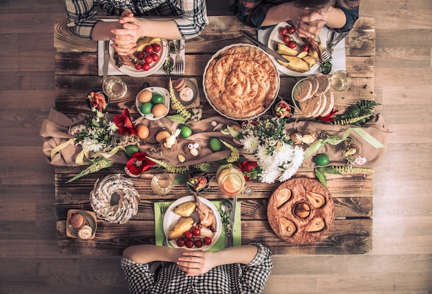 Photo holiday friends or family at the festive table top view. friends pray in honor of easter at the festive table