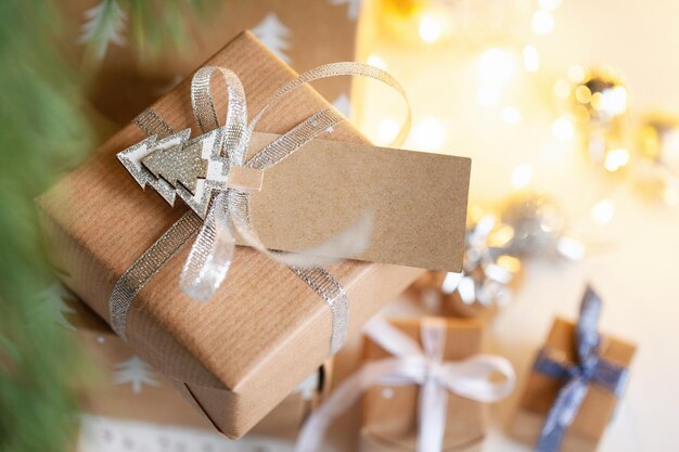 Confezione regalo per le vacanze regalo di natale con etichetta della scheda dell'indirizzo sotto l'abete sul pavimento della camera concetto di natale