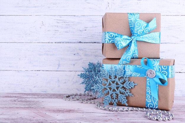 Holiday gift boxes decorated with blue ribbon on table on wooden wall background