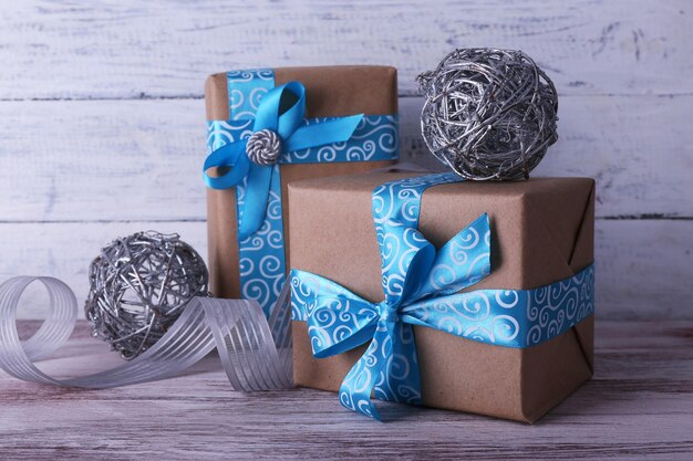 Holiday gift boxes decorated with blue ribbon on table on wooden wall