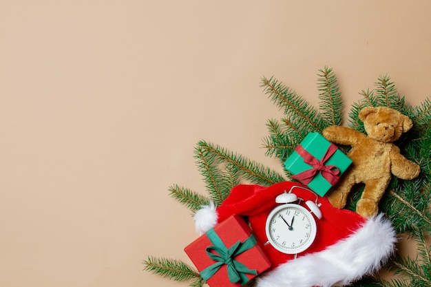 Holiday gift boxes with spruce branches and teddy bear with alarm clock on stark white color background. Above view