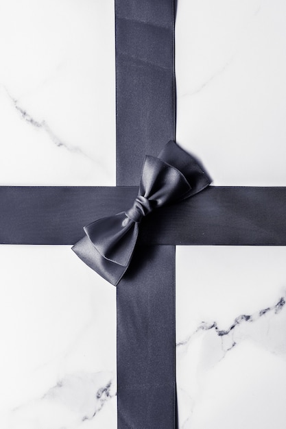Holiday gift decoration and sale promotion concept  black silk ribbon and bow on marble background f...