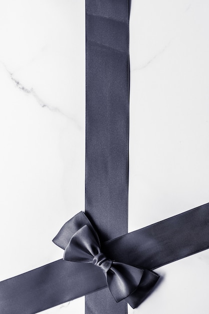 Decorazione regalo di festa e concetto di promozione della vendita nastro di seta nera e fiocco su sfondo marmo f...