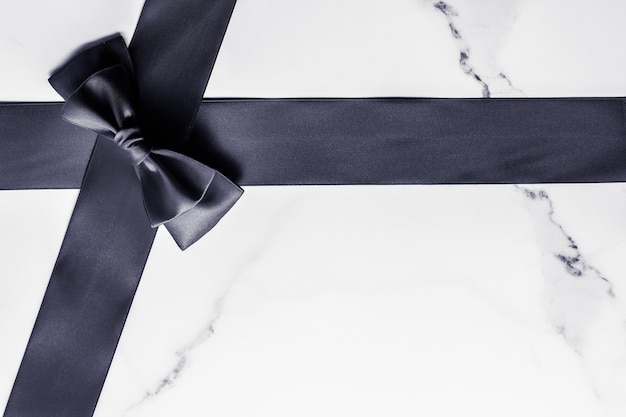 Holiday gift decoration and sale promotion concept  black silk ribbon and bow on marble background f...