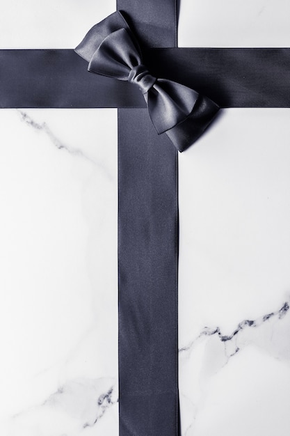 Holiday gift decoration and sale promotion concept  black silk ribbon and bow on marble background f...