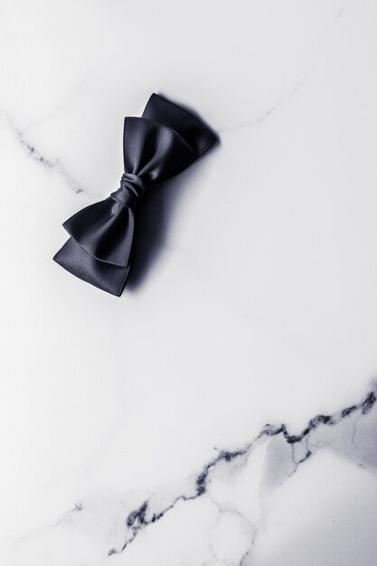 ホリデーギフトの装飾と販売促進のコンセプト黒のシルクリボンと大理石の背景の弓...