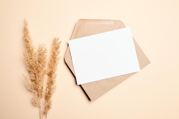 Holiday greeting card mockup with dry grass on beige background top view flat lay White wedding invitation card