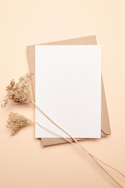 Holiday greeting card mockup with dry grass on beige background top view flat lay White wedding invitation card