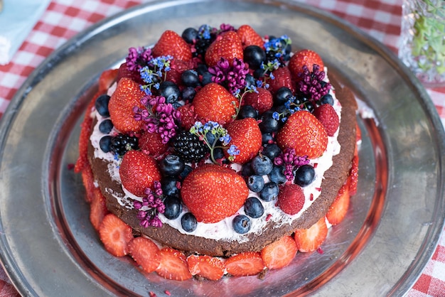 Holiday homemade chocolate cake with whipped cream berries and edible flowers