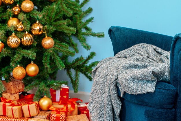 休日のインテリア、美しい装飾が施された青い肘掛け椅子とクリスマスツリー