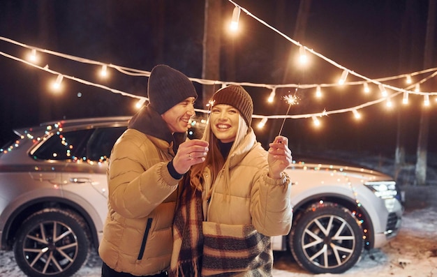 Holiday lights Couple standing in the forest and celebrating New year