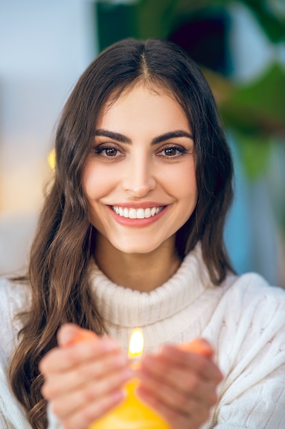 Holiday mood. Young beautiful woman in white clothes holding a burning candle