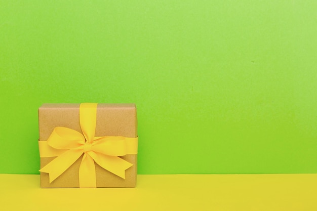 휴일 종이 선물은 복사 공간이 있는 노란색 리본 활 상단 보기를 묶었습니다. 평면 누워 휴일 배경 생일 또는 크리스마스 선물 복사 공간이 있는 크리스마스 선물 상자 개념