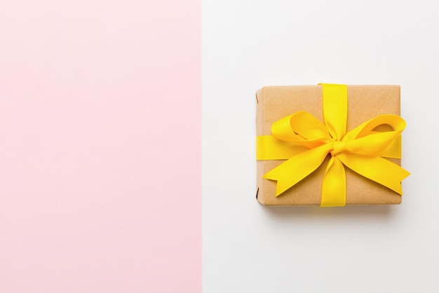 Holiday paper present tied yellow ribbon bow top view with copy space Flat lay holiday background Birthday or christmas present Christmas gift box concept with copy space