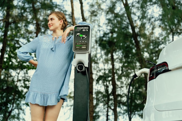 Foto vacanze su strada con una bella giovane donna e un'auto elettrica perpetua