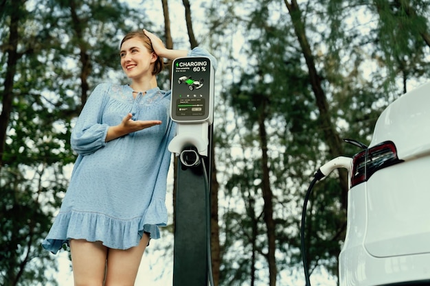 Foto vacanze su strada con una bella giovane donna e un'auto elettrica perpetua