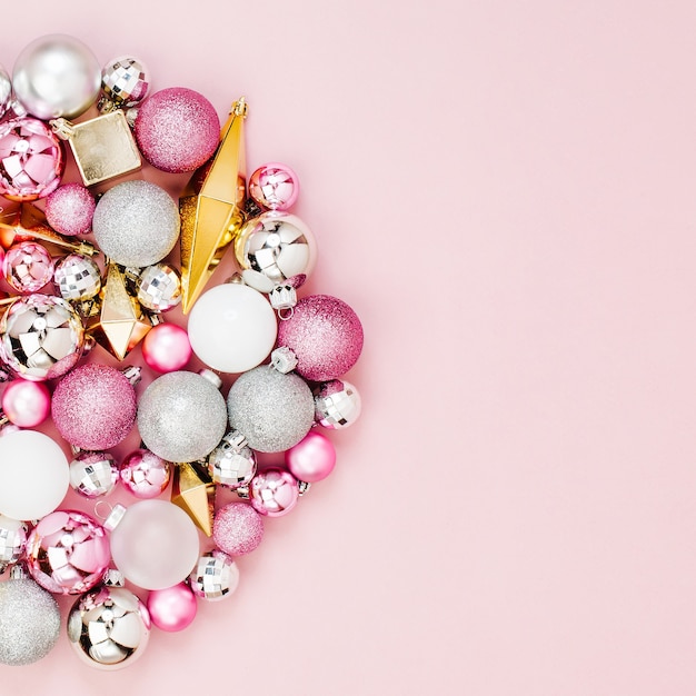 Holiday round arrangement with Stylish Christmas shiny balls and gold crystals on pastel pink background. Flat lay, top view