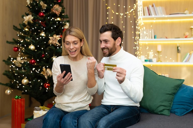 Праздничная распродажа интернет-магазинов молодая семья пара мужчина и женщина дома возле рождества
