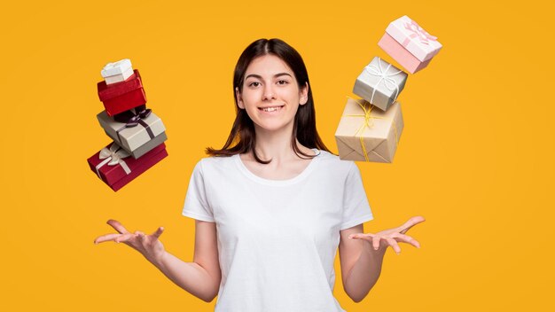 Holiday shopping discount sale amused woman in white tshirt\
throwing up gift boxes in air isolated on orange happy birthday\
festive fun birthday greeting