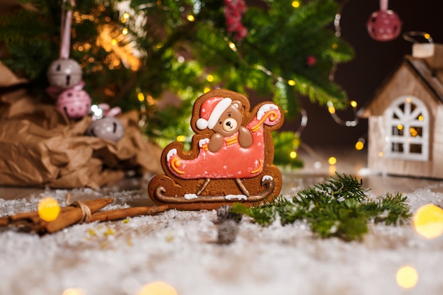 Holiday traditional food bakery. Gingerbread christmas bear in sleigh in cozy decoration with garland lights