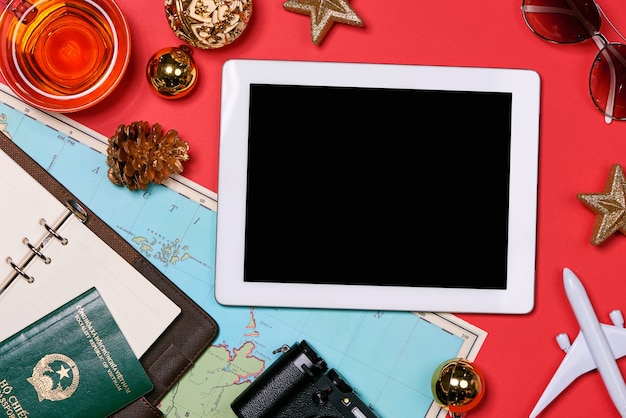 Concetto di viaggio holiday - passaporto, macchina fotografica, cappello, aereo, decorazioni natalizie su sfondo rosso