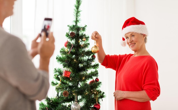 写真 休日と人々のコンセプト - クリスマスツリーを飾り,写真にポーズをとる幸せな上級女性