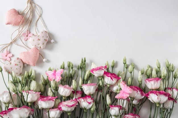 Sfondo di vacanze: su sfondo bianco rosa con fiori bianchi e cuori