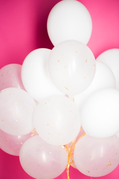 holidays, birthday, party and decoration concept - close up of inflated white helium balloons over pink background