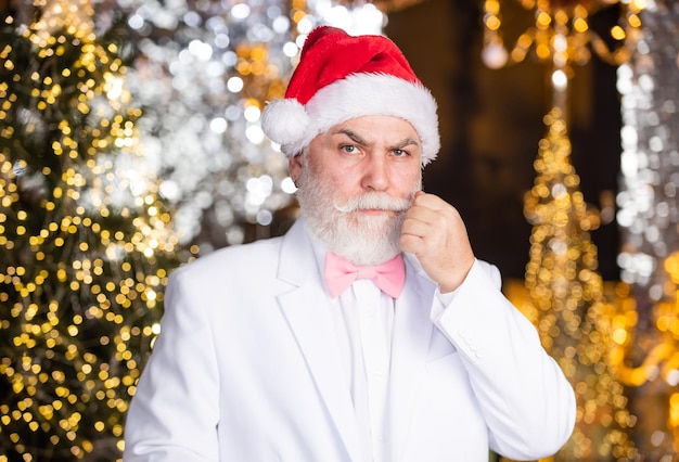 休日のお祝い ひげを生やした年配の男性 おめでとう ひげを生やした祖父の男がクリスマスを祝います クリスマスイブ サンタクロース スーツを着たエレガントなおじいちゃん クリスマス企業