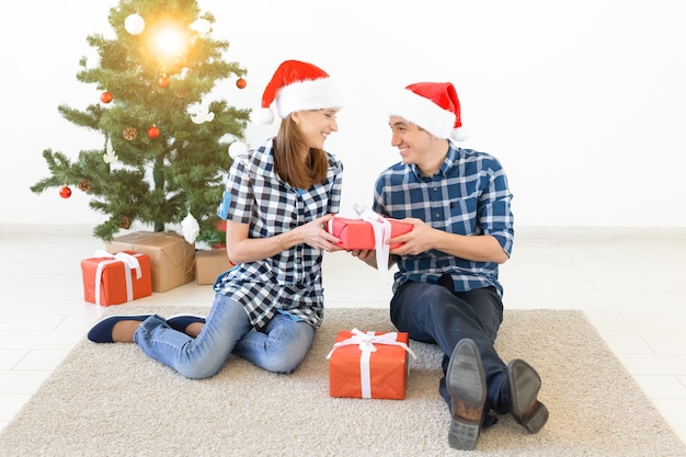 休日、クリスマス、家族のコンセプト-愛する幸せなカップルが自宅でギフトを開く