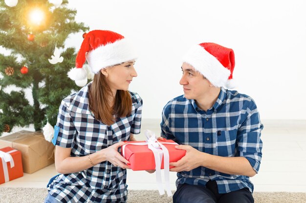 Vacanze, natale e concetto di famiglia - amorevole coppia felice che apre i regali a casa