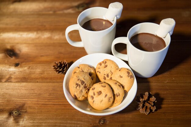 休日、クリスマス、冬、食べ物と飲み物のコンセプト - ホット チョコレートやココアの飲み物とマシュマロ オート麦クッキー木製テーブルの上のカップのクローズ アップ