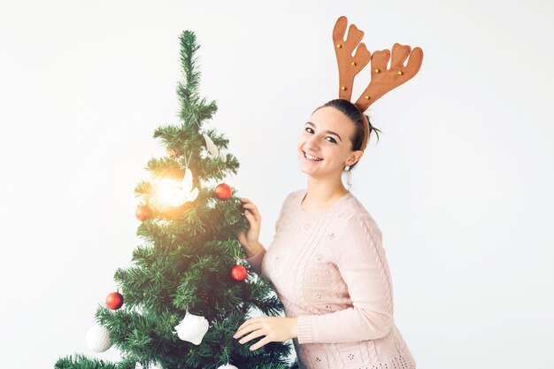 Holidays concept - Funny young woman decorated christmas tree on white background. Waiting for christmas.