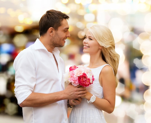 휴일, 데이트, 사람 및 데이트 개념 - 조명 배경 위에 꽃 다발을 가진 행복한 커플
