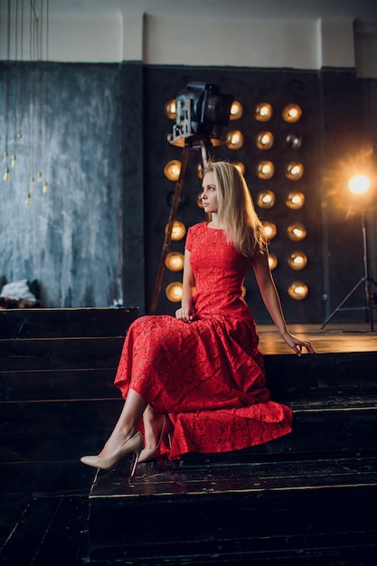 Foto feste e concetto di modo - bella donna sexy in vestito rosso sopra il fondo delle luci