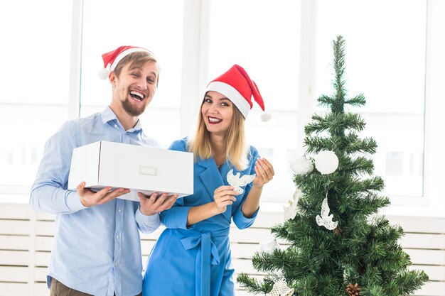 Holidays and festive concept - Young family couple decorating the christmas tree.