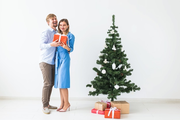 Holidays and festive concept - Young happy couple near a Christmas tree on white space