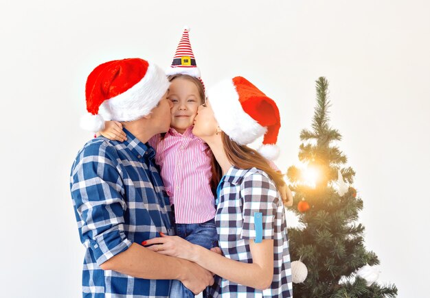 Vacanze, regali e concetto di albero di natale - piccola famiglia che si diverte insieme a natale