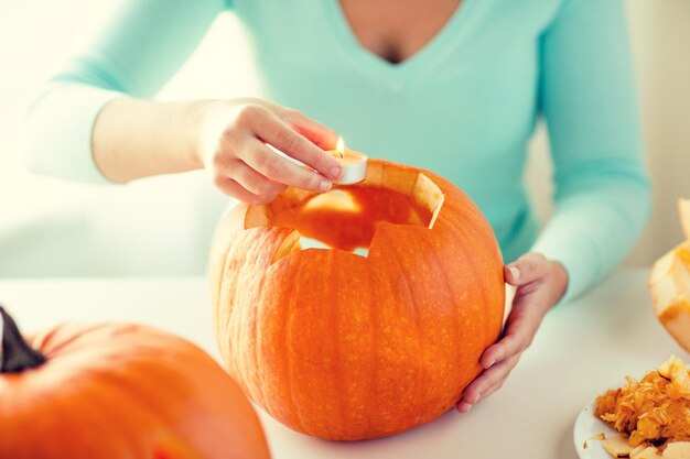 holidays, halloween, decoration and people concept - close up of woman with pumpkins at home