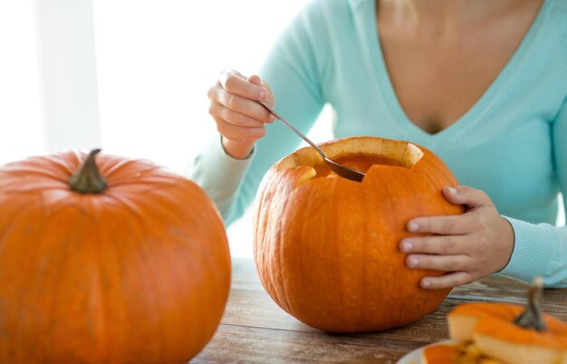 holidays, halloween, decoration and people concept - close up of woman with pumpkins at home