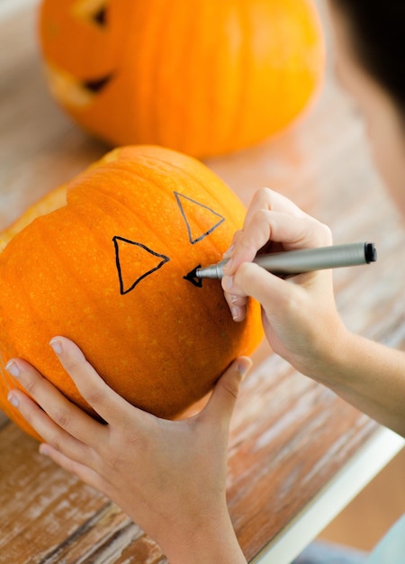 holidays, halloween, decoration and people concept - close up of woman with pumpkins at home