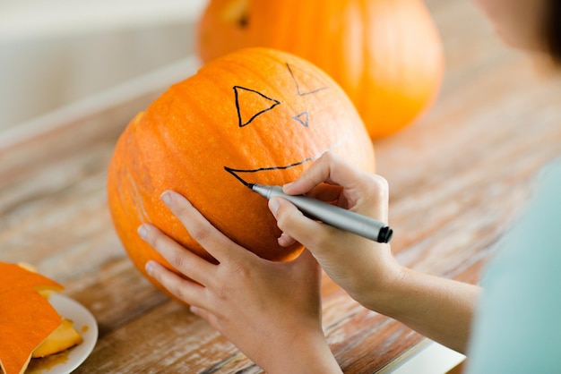 holidays, halloween, decoration and people concept - close up of woman with pumpkins at home