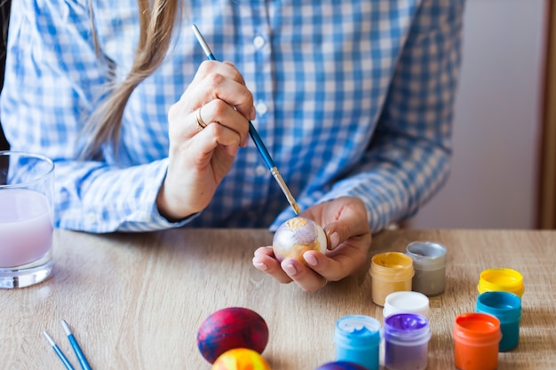 Vacanze, concetto di creazione e fatto a mano - la ragazza attinge all'uovo di pasqua, primo piano.