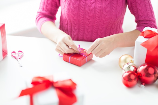 праздники, люди и концепция празднования - крупный план женщины, украшающей рождественские подарки