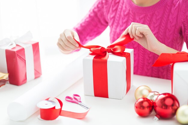 праздники, люди и концепция празднования - крупный план женщины, украшающей рождественские подарки