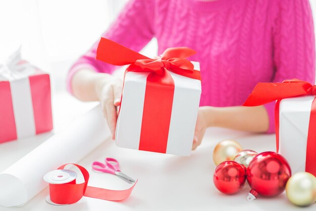 holidays, people and celebration concept - close up of woman decorating christmas presents