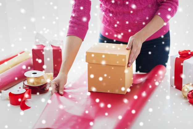 holidays, people and celebration concept - close up of woman decorating christmas presents