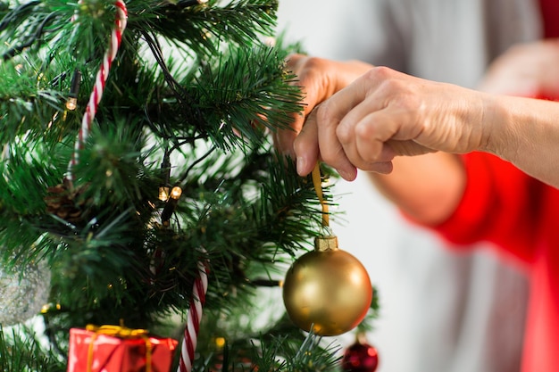 holidays and people concept - close up of happy senior woman decorating christmas tree